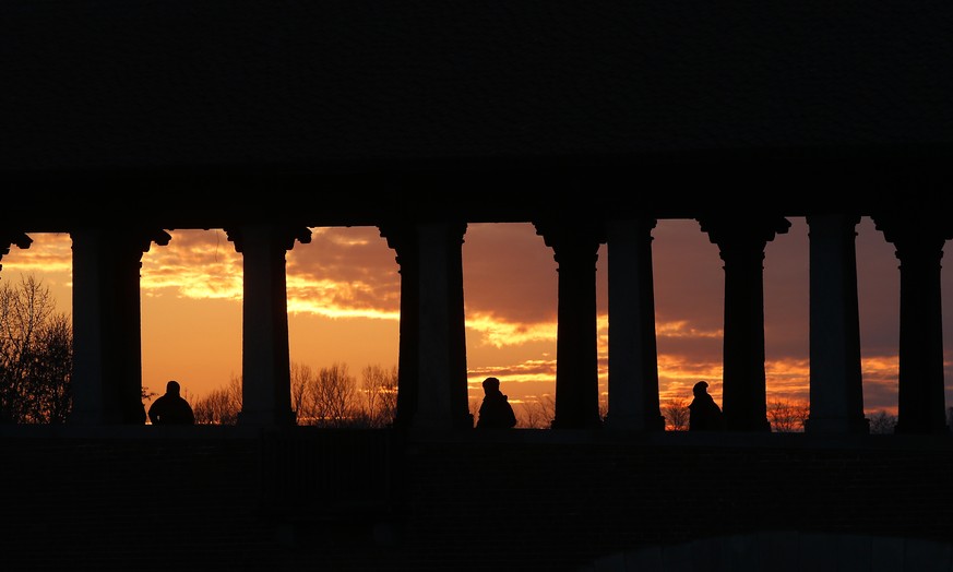 People walk at sunset along the Ponte Coperto (Covered bridge), also known as Ponte Vecchio (Old Bridge), a brick and stone arch bridge over the Ticino River, in Pavia, some 40 kilometers (24 miles) f ...