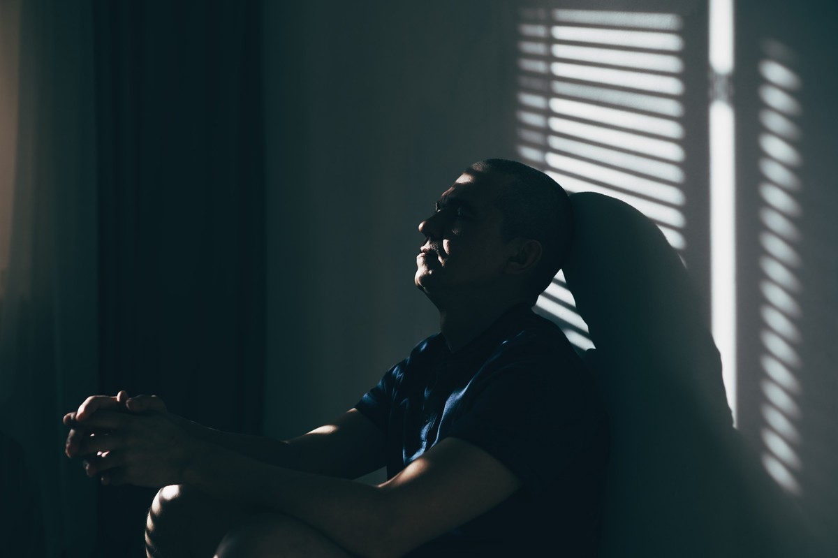 depressed man sitting head in hands on the bed in the dark bedroom with low light environment, dramatic concept