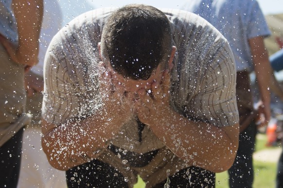 Ein Schwinger kuehlt sich am Brunnen mit kuehlem Wasser ab, fotografiert im 3. Gang beim Innerschweizer Schwing - und Aelplerfest vom Sonntag 5. Juli 2015 in Seedorf im Kanton Uri. Nach den gestrigen  ...