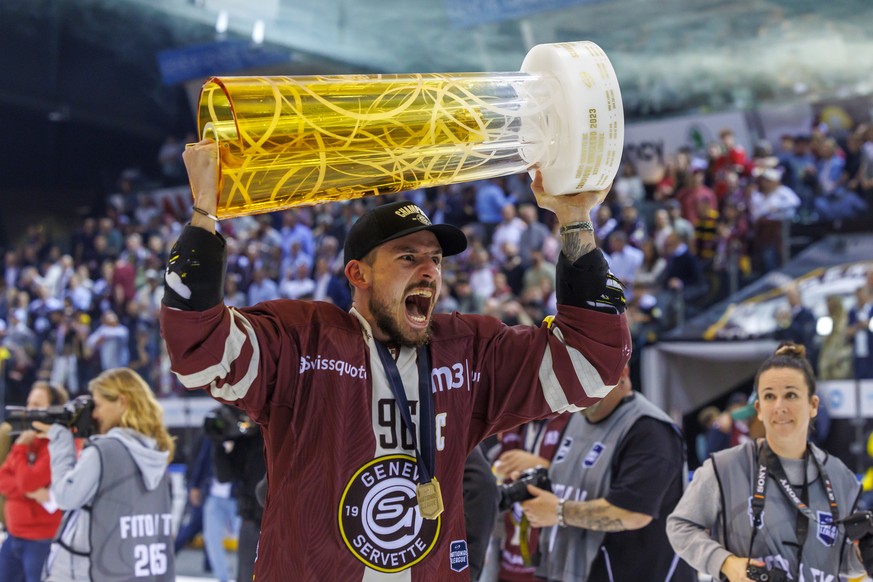 Geneva Servette forward Noah Rudd celebrates with the Swiss Champion's Cup after winning 4:1 in the seventh and final first leg of the Swiss National League Ice Hockey Final...