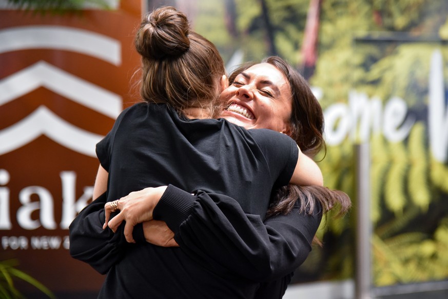 epa09144505 Families and loved ones embrace after landing on the first Air New Zealand flight to land, on the first day of the trans-Tasman bubble, in Wellington, New Zealand, 19 April 2021. EPA/BEN M ...