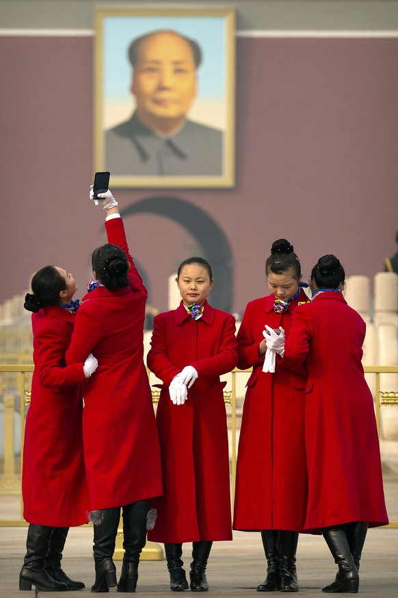 Hospitality staff members pose for a selfie near the portrait of Chinese leader Mao Zedong during the opening session of the Chinese People&#039;s Political Consultative Conference (CPPCC) held in Bei ...