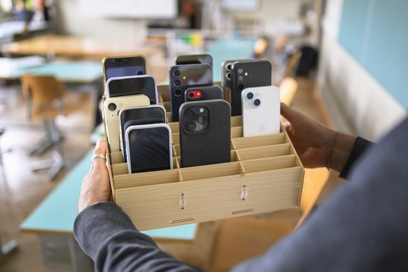 Eine Lehrperson bringt eine Handygarage mit den Mobiltelefonen seiner Schueler ins Klassenzimmer, fotografiert am Donnerstag, 8. Mai 2025 an einer Schule in Bern. (KEYSTONE/Christian Beutler)