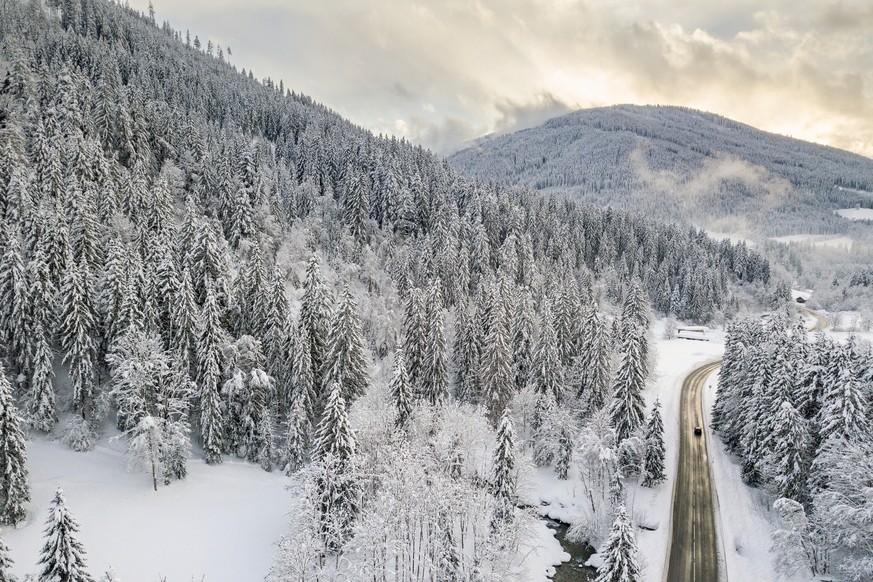 epa07269912 A picture taken with a drone shows a car driving on a road through the snow covered landscape near Filzmoos, Austria, 08 January 2018. Media reports state that many regions in Austria, Ger ...