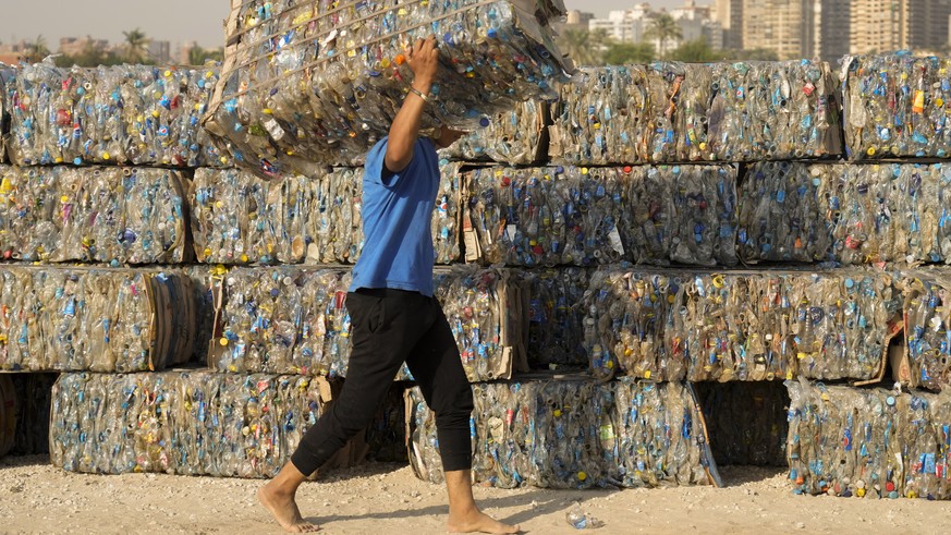 FILE - &quot;Verynile&quot; initiative worker carries compressed plastic bottles which were collected by volunteers and fishermen from the Nile to build a Plastic Pyramid ahead of World Cleanup Day in ...