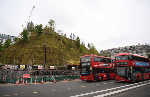 epa09364796 Construction workers finish work of the Marble Arch Mound in London in Britain, 25 July 2021. The temporary Marble Arch Mound will include a viewing platform which allows visitors an oppor ...