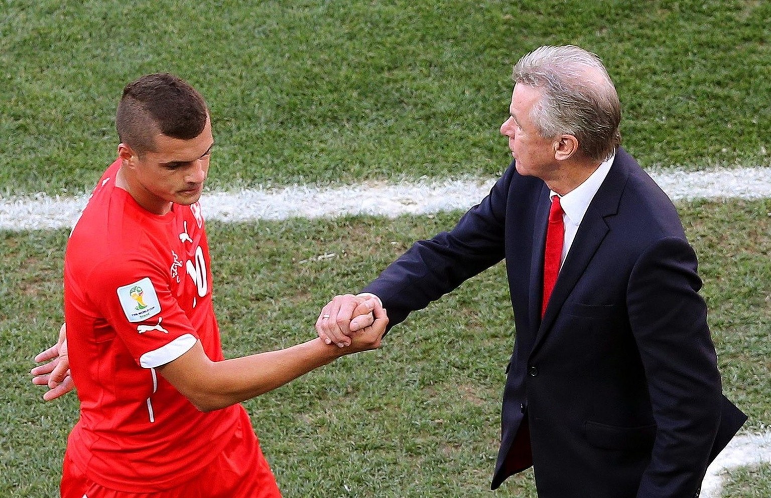 epa04294167 Granit Xhaka (L) of Switzerland shakes hands with head coach Ottmar Hitzfeld (R) as he leaves the pitch during the FIFA World Cup 2014 round of 16 match between Argentina and Switzerland a ...