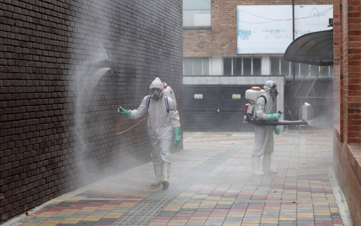 Worker in full protective gear amid the new coronavirus pandemic disinfect an alleyway at Corabastos, one of Latin America's largest food distribution centers, in Bogota, Colombia, Tuesday, June  ...