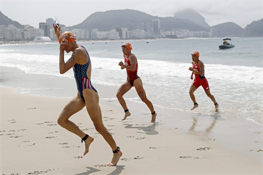 epa05502094 (L-R) Gwen Jorgensen of the USA, Nicola Spirig of Switzerland, and Barbara Riveros of Chile return to Copacobana beach after completing the swimming leg of the women&#039;s Triathlon race  ...