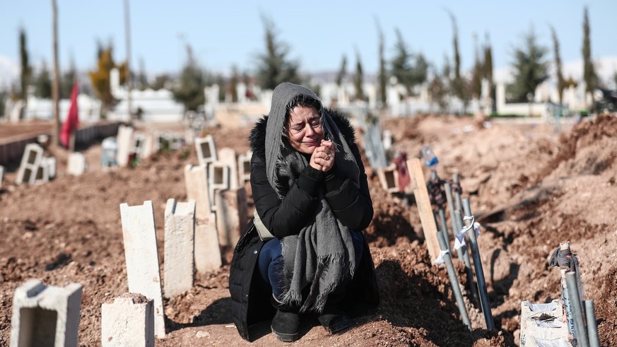 epa10460909 A woman mourns her relatives at a mass grave area following a major earthquake in Adiyaman, southeastern Turkey, 11 February 2023. More than 24,000 people have died and thousands more are  ...