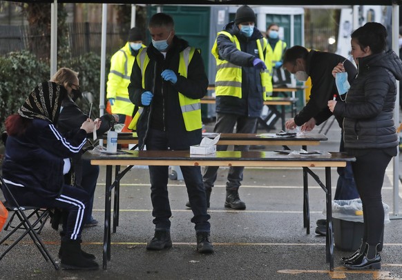 People take their own COVID-19 swab test at a newly set-up testing facility in a car park in West Ealing, London, Tuesday, Feb. 2, 2021. British health authorities plan to test tens of thousands of pe ...