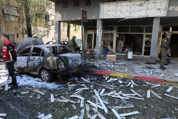 epa09201379 Israeli emergency teams and police inspect at the scene where a rocket fired from the Gaza Strip hit in the central city of Ramat Gan near Tel Aviv, Israel, 15 May 2021. In response to day ...