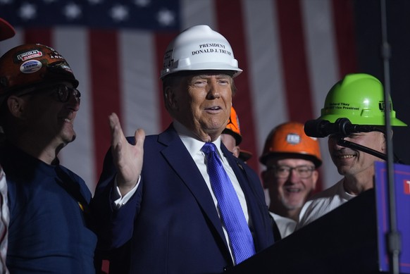 Republican presidential nominee former President Donald Trump stands on stage with steelworkers as he speaks during a campaign rally at Arnold Palmer Regional Airport, Saturday, Oct. 19, 2024, in Latr ...