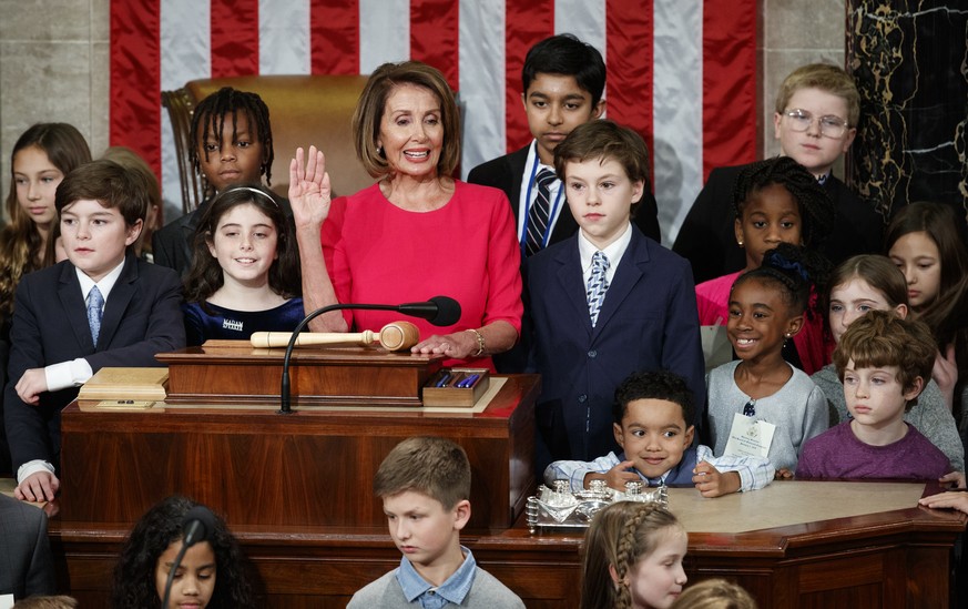 Nancy Pelosi of California, surrounded by her grandchildren and other children raises her right hand as Rep. Don Young, R-Alaska, the longest-serving member of the House, administers the oath to Pelos ...