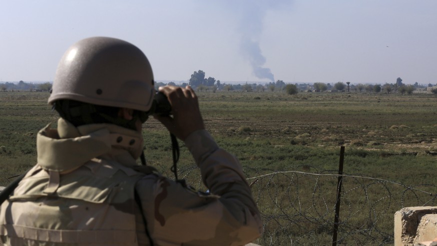 In this Tuesday, Nov. 13, 2018 photo, an Iraqi soldier watches smoke rising after an airstrike by US-led International coalition warplanes against ISIS, on the border between Syria and Iraq in Qaim, A ...