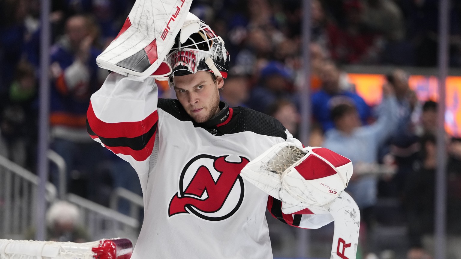 New Jersey Devils goaltender Akira Schmid (40) adjusts his helmet as he reacts after New York Islanders&#039; Bo Horvat scored a goal during the second period of an NHL hockey game Friday, Oct. 20, 20 ...