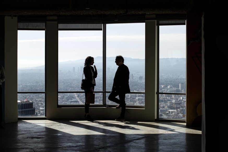 epa10548261 Guests interact in front of a window on the 61st empty floor of the US Bank Tower, during the unveiling of a series of improvements to the building to officials and the press in Los Angele ...
