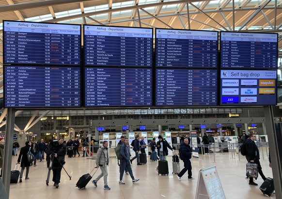 epa08205320 Commuters look at display boards displayig cancelled flights, at the airport of Hamburg, Germany, 09 February 2020. According to the German Weather Service (DWD), storm Sabine will spread to the north and center of Germany during the course of the day with heavy winds and individual hurricane gusts. Deutsche Bahn is expecting train cancellations, German carrier Lufthansa disruptions in air traffic.  EPA/JOERG SCHIERENBECCK
