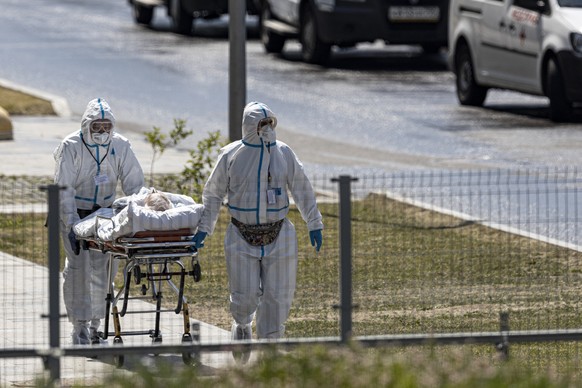 FILE - In this June 26, 2021, file photo, medical workers carry a patient suspected of having coronavirus on a stretcher at a hospital in Kommunarka, outside Moscow, Russia. Countries across Europe ar ...