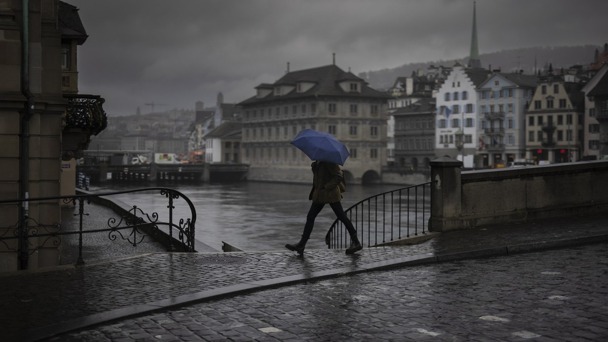 A woman walks in the rain with an umbrella across the Muensterbridge over the river Limmat, on Tuesday, November 21, 2023 in Zurich, Switzerland. (KEYSTONE/Michael Buholzer)