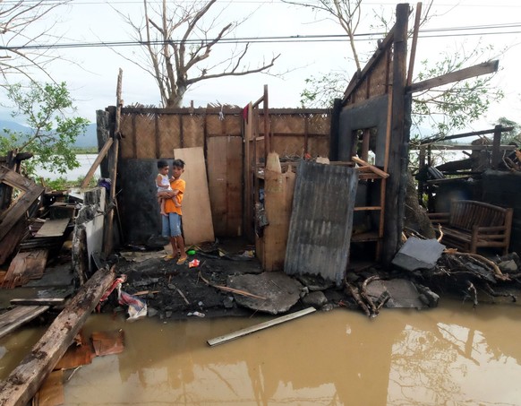 epa05688386 Filipino villagers stand insde a damaged home in the typhoon-hit town of Polangui, Albay province, Philippines, 26 December 2016. According to an Office of Civil Defense (OCD) report on 26 ...