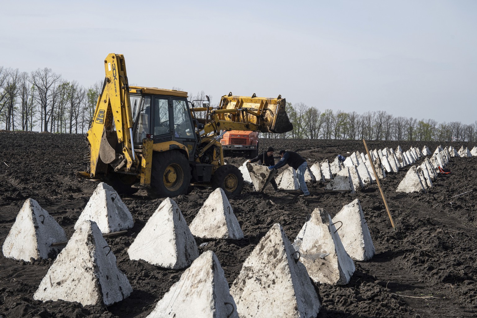 Workers install anti-tank systems known as ?dragon teeth? during construction new defensive positions close to the Russian border in Kharkiv region, Ukraine, on Wednesday, April 17, 2024. (AP Photo/Ev ...