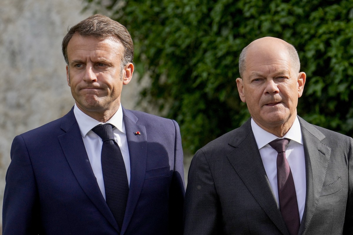 German Chancellor Olaf Scholz, right, and French President Emmanuel Macron walk through the garden the German government guest house Meseberg Palace to the Franco-German Ministerial Council in Meseber ...