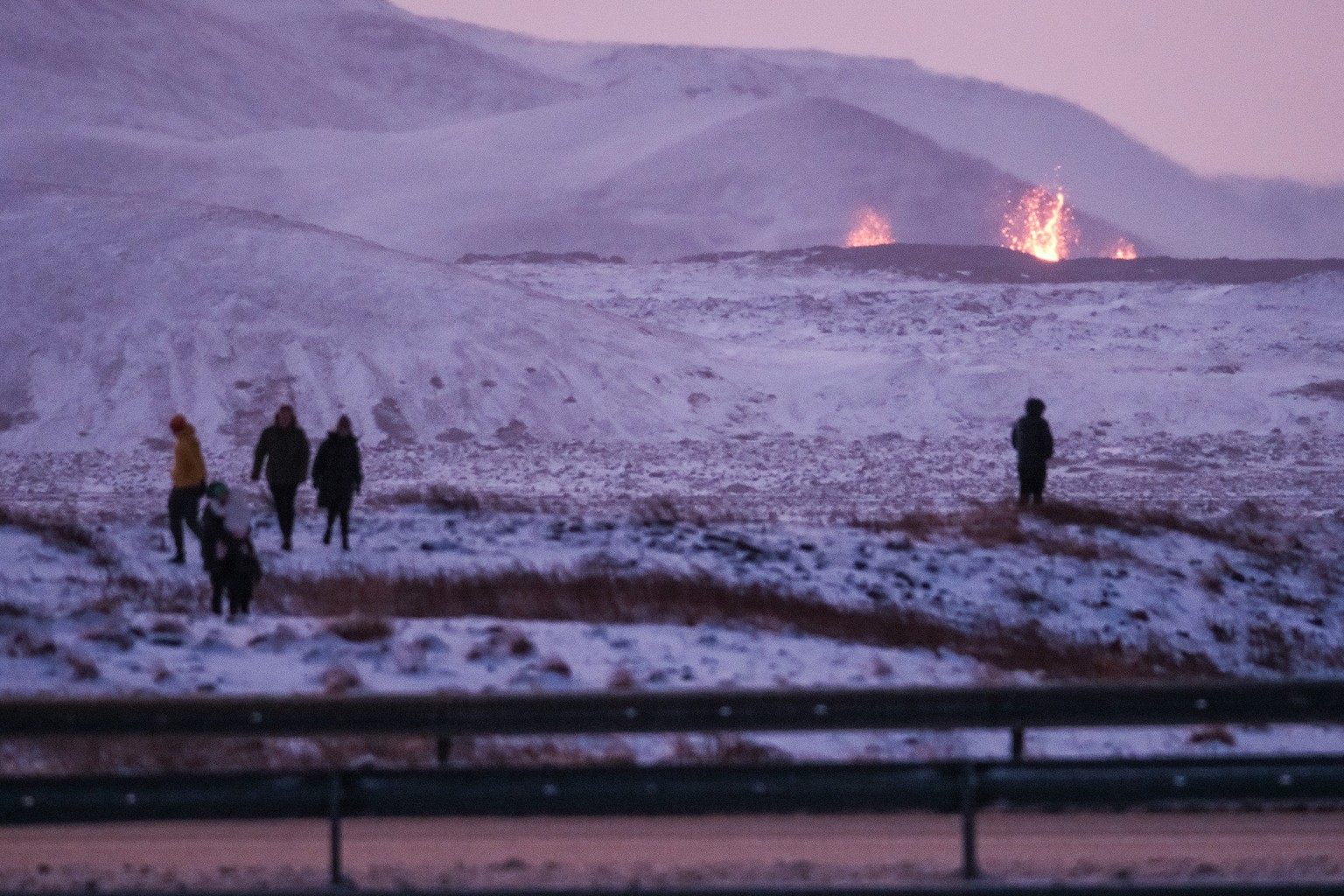 epa11037005 Onlookers gather to watch the lava flow after a volcanic eruption near the town of Grindavik, Reykjanes peninsula, Iceland, 19 December 2023. The start of a volcanic eruption was announced ...