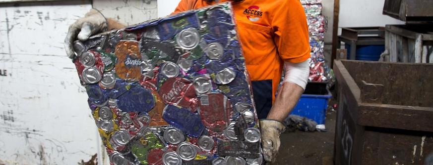Yard Manager Joel Landon-Lane carries a compressed block of aluminium cans at a metal recycling facility in Sydney, February 18, 2014. Aluminium producer Alcoa Inc said it will close its Point Henry s ...
