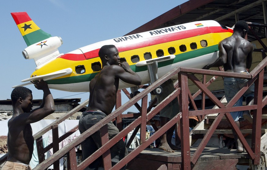 -PHOTO TAKEN 22JAN06- Carpenters carry a coffin shaped in the form of a Ghana Airways aircraft to their showroom in Teshie, a suburb of the Ghanaian capital of Accra, January 22, 2004. Funerals are im ...