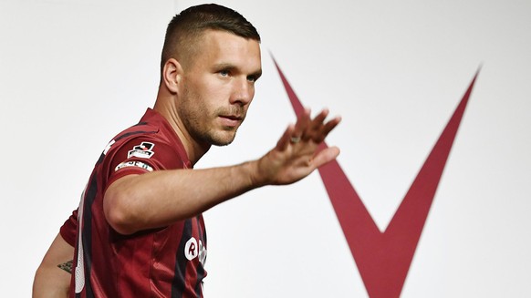 German striker Lukas Podolski wearing a new jersey of Japanese club Vissel Kobe waves at Kobe fans during a press conference in Kobe, western Japan, Thursday, July 6, 2017. Kobe rolled out the red car ...