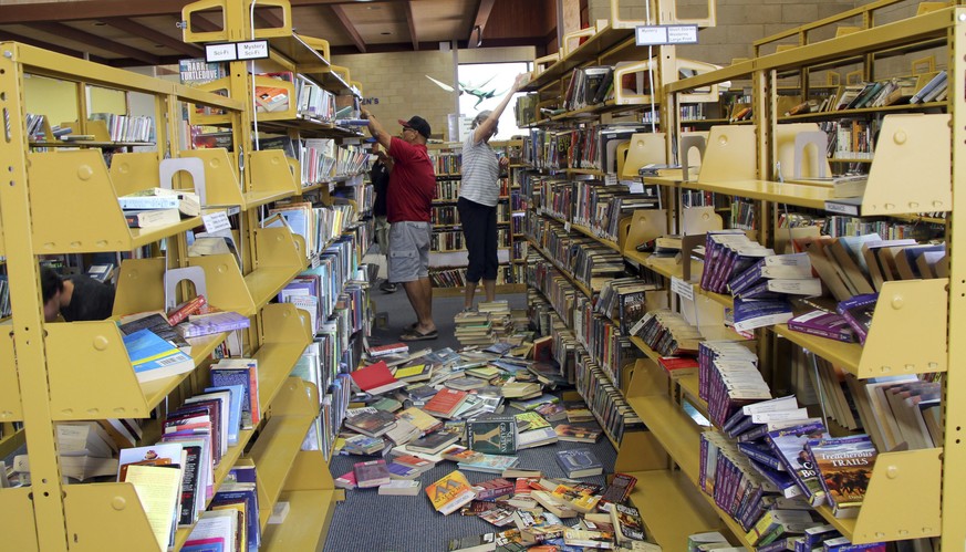 Some shelves are nearly empty as volunteers assist with cleanup at the Ridgecrest, Calif., branch of the Kern County Library on Friday, July 5, 2019, following a 6.4 magnitude earthquake that shook th ...