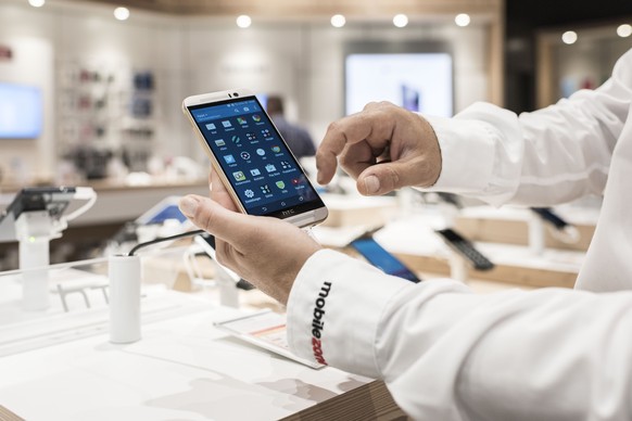 ARCHIVBILD ZUM ENTSCHEID DES BUNDESRATES GEGEN ZU HOHE ROAMING-TARIFE VORGEHEN ZU WOLLEN, AM DONNERSTAG, 7. SEPTEMBER 2017 - An employee works on a mobile phone at a Mobilezone Shop of the Mobilezone  ...