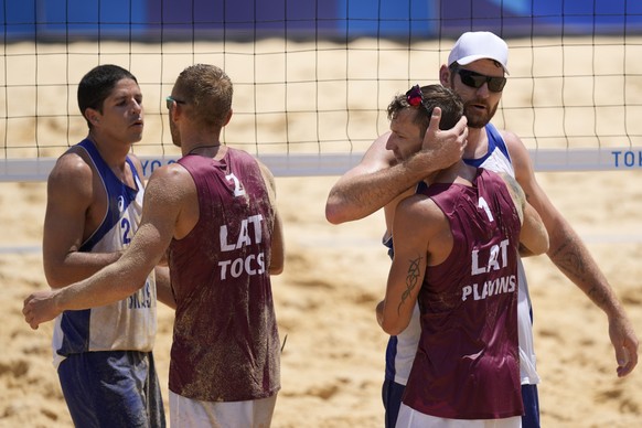 Alvaro Morais Filho, left, of Brazil, hugs Edgars Tocs, second from left, of Latvia, as Alison Cerutti, of Brazil, hugs Martins Plavins, of Latvia, right, after Latvia won a men&#039;s beach volleybal ...