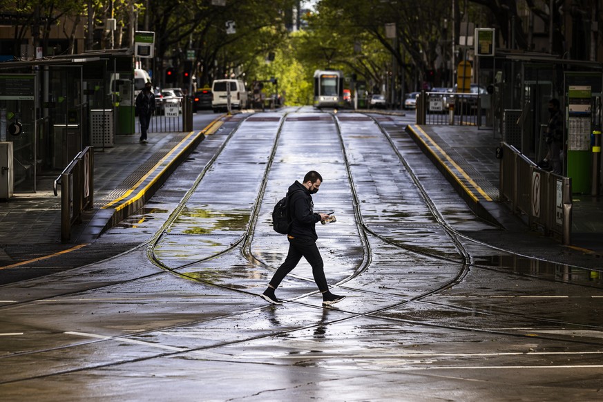 epa09504855 A lone person crosses Collins Street in Melbourne, Victoria, Australia, 04 October 2021. Melbourne has become the most locked down city in the world since the beginning of the COVID-19 pan ...