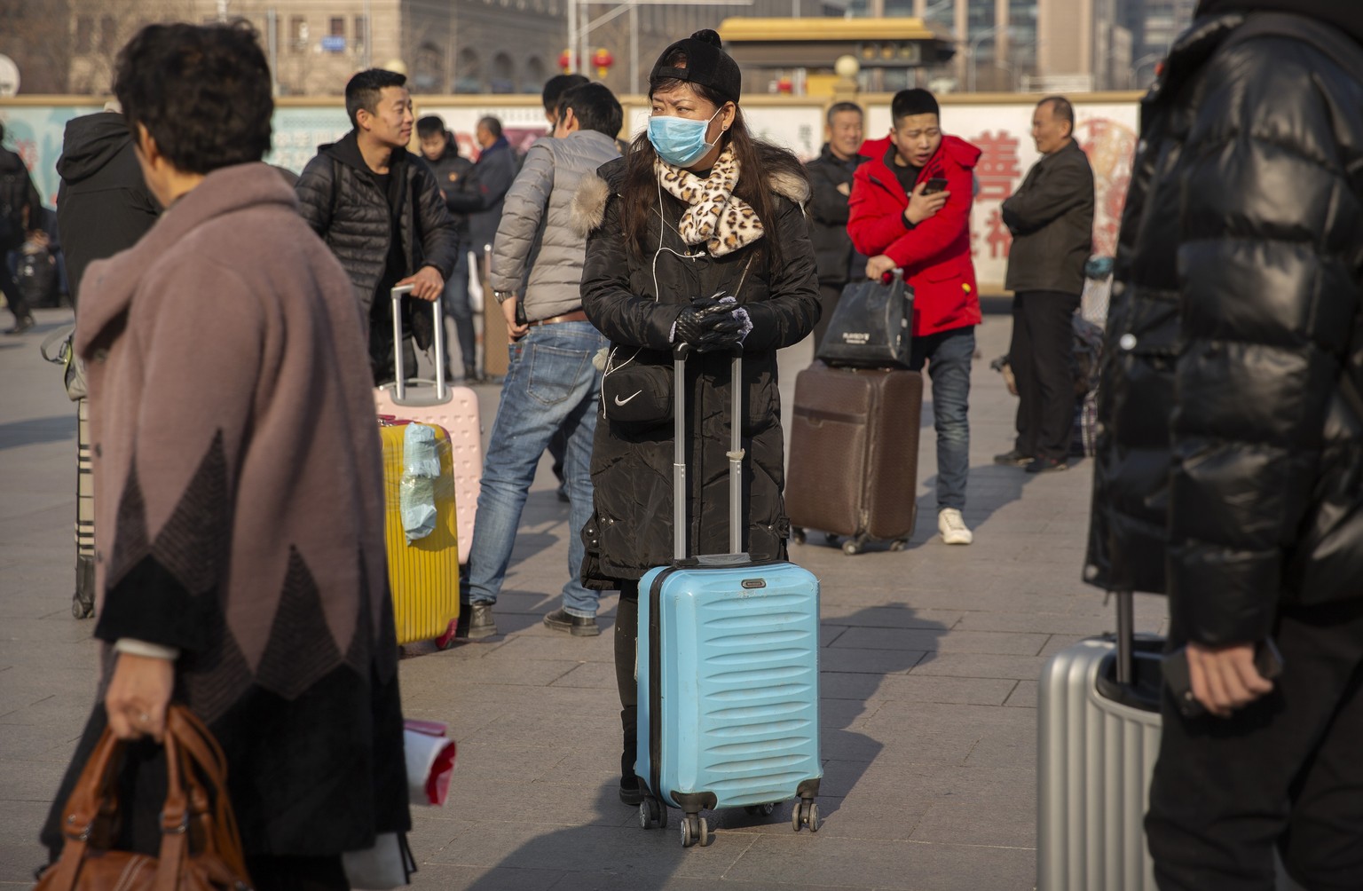 A traveler wears a facemask as she stands near the Beijing Railway Station in Beijing, Friday, Jan. 17, 2020. A second person has died from a new form of coronavirus in central China, health authoriti ...