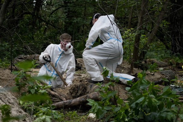 Members of an extraction crew work during an exhumation at a mass grave near Bucha, on the outskirts of Kyiv, Ukraine, Monday, June 13, 2022. (AP Photo/Natacha Pisarenko)