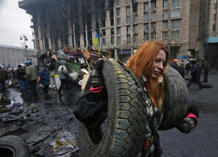 Euromaidan: Eine Frau trägt Reifen zu einer Strassenbarrikade. 