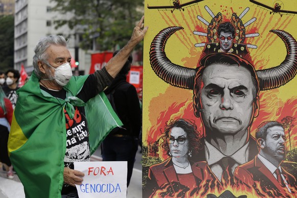 A demonstrator poses for a photo next to a banner depicting Brazilian President Jair Bolsonaro during a protest demanding Bolsonaro resign, in Sao Paulo, Brazil, Saturday, July 3, 2021. Activists call ...
