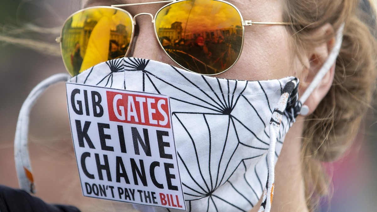 The Reichstag building, home of the German federal parliament, is mirrored in the glasses of a woman wearing a face mask with the slogan "Don't Give (Bill) Gates A Chance" during a demo ...