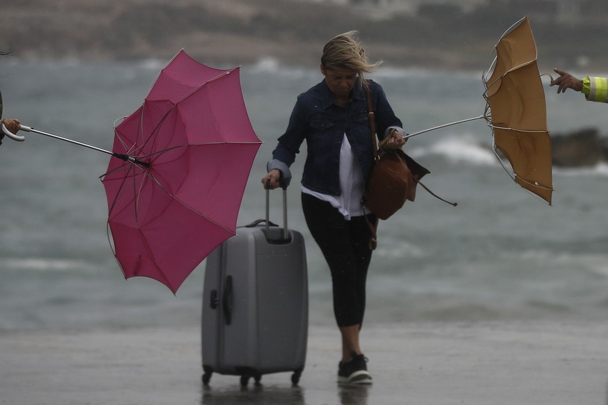 epa07054000 A woman holding an umbrella tries to protect herself from the wind and rain as she walks on a dock at the port of Rafina, near Athens, Greece, 28 September 2018. GreeGreece&#039;s civil pr ...