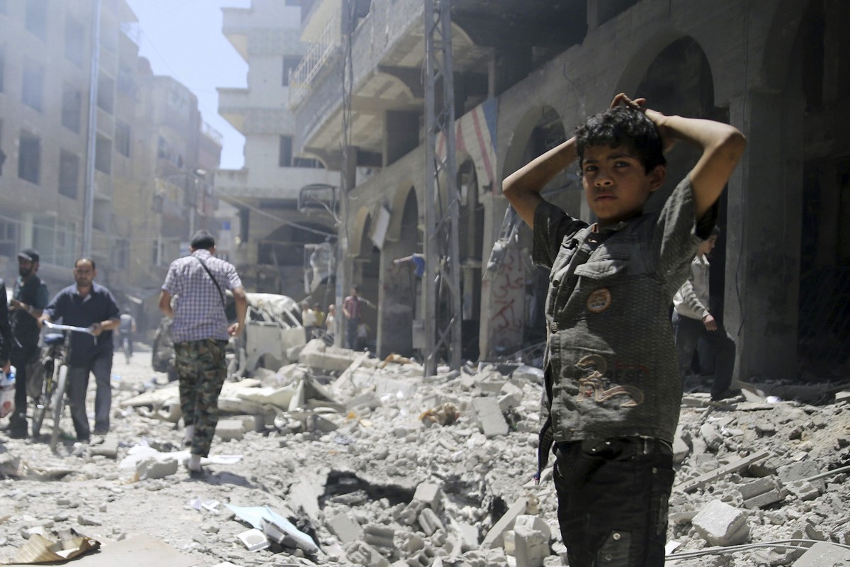 A boy stands amid debris while residents inspect damage after what activists claimed was shelling by forces loyal to Syrian President Bashar al-Assad at a market in central Duma in the eastern al-Ghou ...