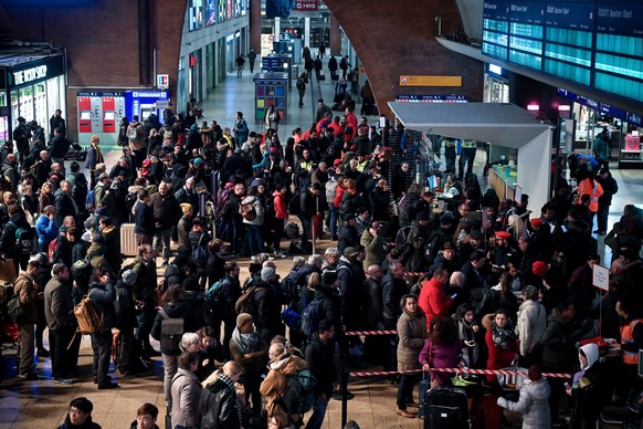 Passagiere, die am Hauptbahnhof Köln festsitzen, stehen an, um sich beim Infopersonal der DB zu informieren.