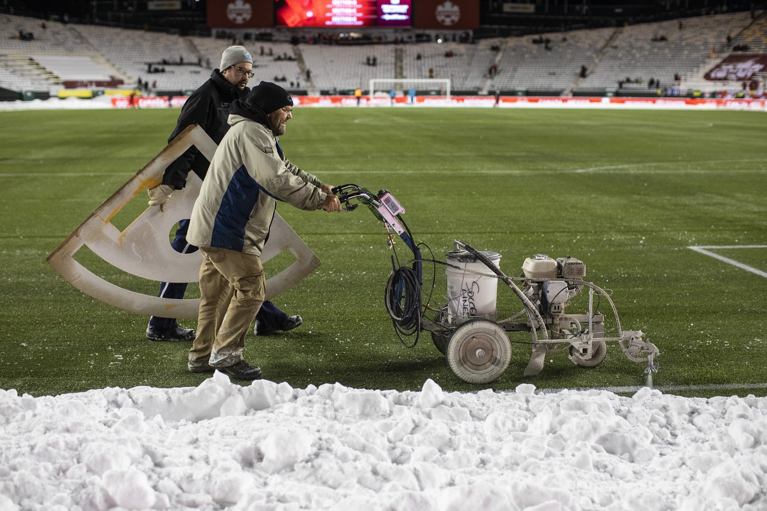 Crews mark the lines after cleaning snow off the field before a FIFA World Cup qualifying soccer match between Canada and Mexico, Tuesday, Nov. 16, 2021, in Edmonton, Alberta. (Jason Franson/The Canad ...