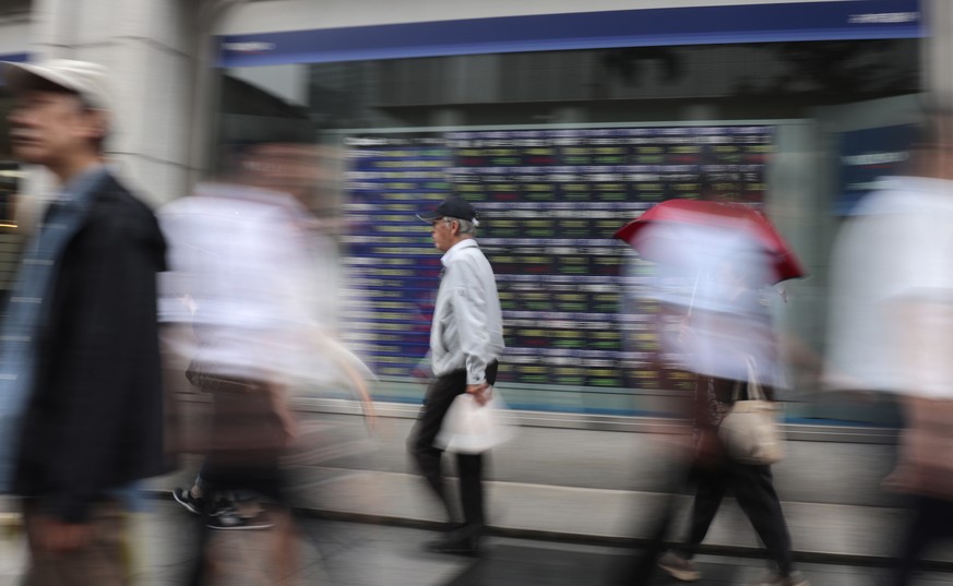 People walk past an electronic stock indicator of a securities firm in Tokyo, Monday, Aug. 14, 2017. Shares were mostly higher in Asia on Monday, although Japan&#039;s Nikkei 225 benchmark fell as ten ...