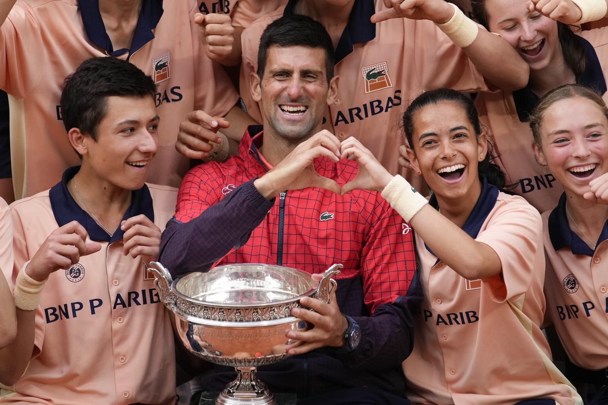Serbia's Novak Djokovic poses with ball girls and boys as he celebrates winning the men's singles final match of the French Open tennis tournament against Norway's Casper Ruud in three  ...