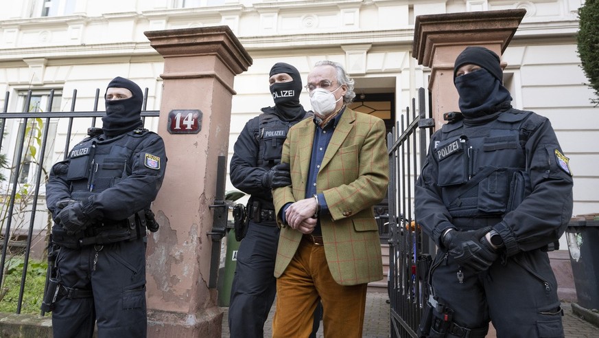 07.12.2022, Hessen, Frankfurt/Main: Bei einer Razzia gegen sogenannte «Reichsbürger» führen vermummte Polizisten, nach der Durchsuchung eines Hauses Heinrich XIII Prinz Reuß (2.v.r.) zu einem Polizeif ...