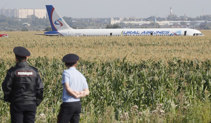 epa07774163 Russian police officers near the site of Ural Airlines A-321 passenger plane emergency landing outside Zhukovsky airport in Ramensky district of Moscow region, Russia, 15 August 2019. A-32 ...