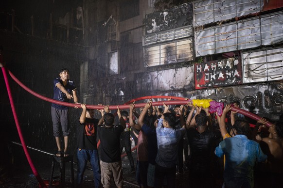 Locals help firefighters contain a fire that broke out at a commercial complex in Dhaka, Bangladesh on Thursday, February 29, 2024.  Bangladesh's health minister says a fire in a six-storey commercial…