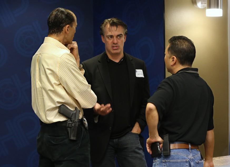 In this photo taken Thursday, Feb. 19, 2015, Rick Smith, chief executive officer and founder of Taser International, center, talks with Brant Garrick left, and Kenny Park of the Vallejo Police Departm ...